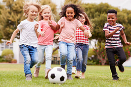 kids chasing soccer ball on grass