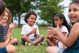 kids sitting in a field clapping